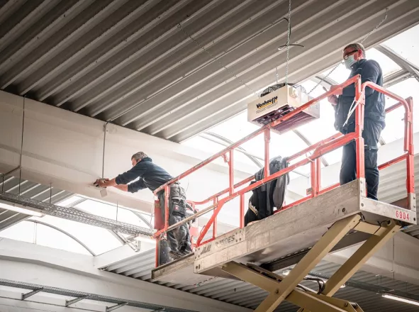 Technici plaatsen een luchtverwarmer in een industriële hal