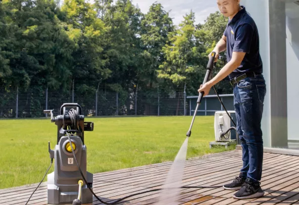 Medewerker reinigt een terras met een hogedrukreiniger
